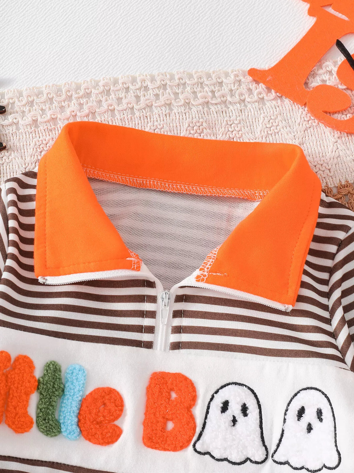 Close-up of the orange collar and half zipper on the brown striped top.