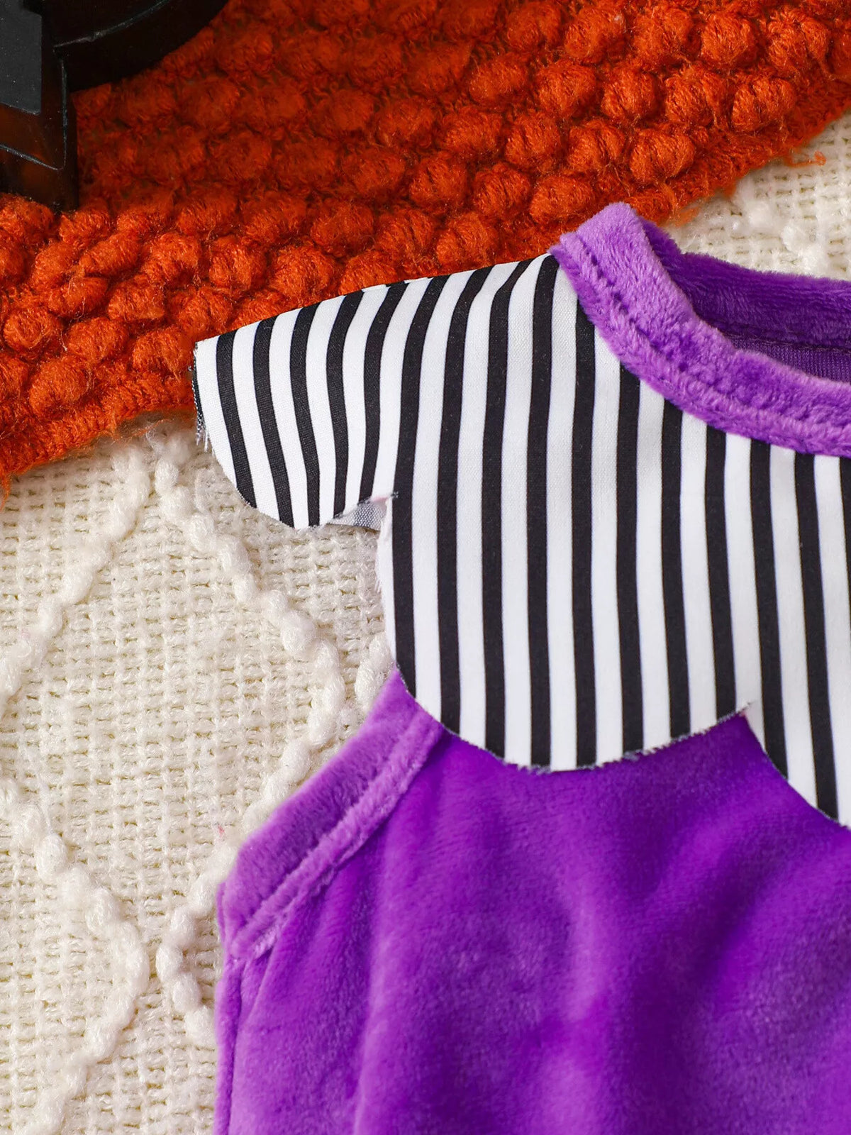 Striped yoke and purple fabric detail of the baby bodysuit