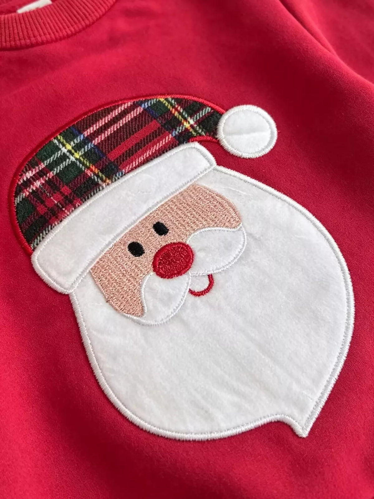 Smiling Santa face graphic on the red sweatshirt