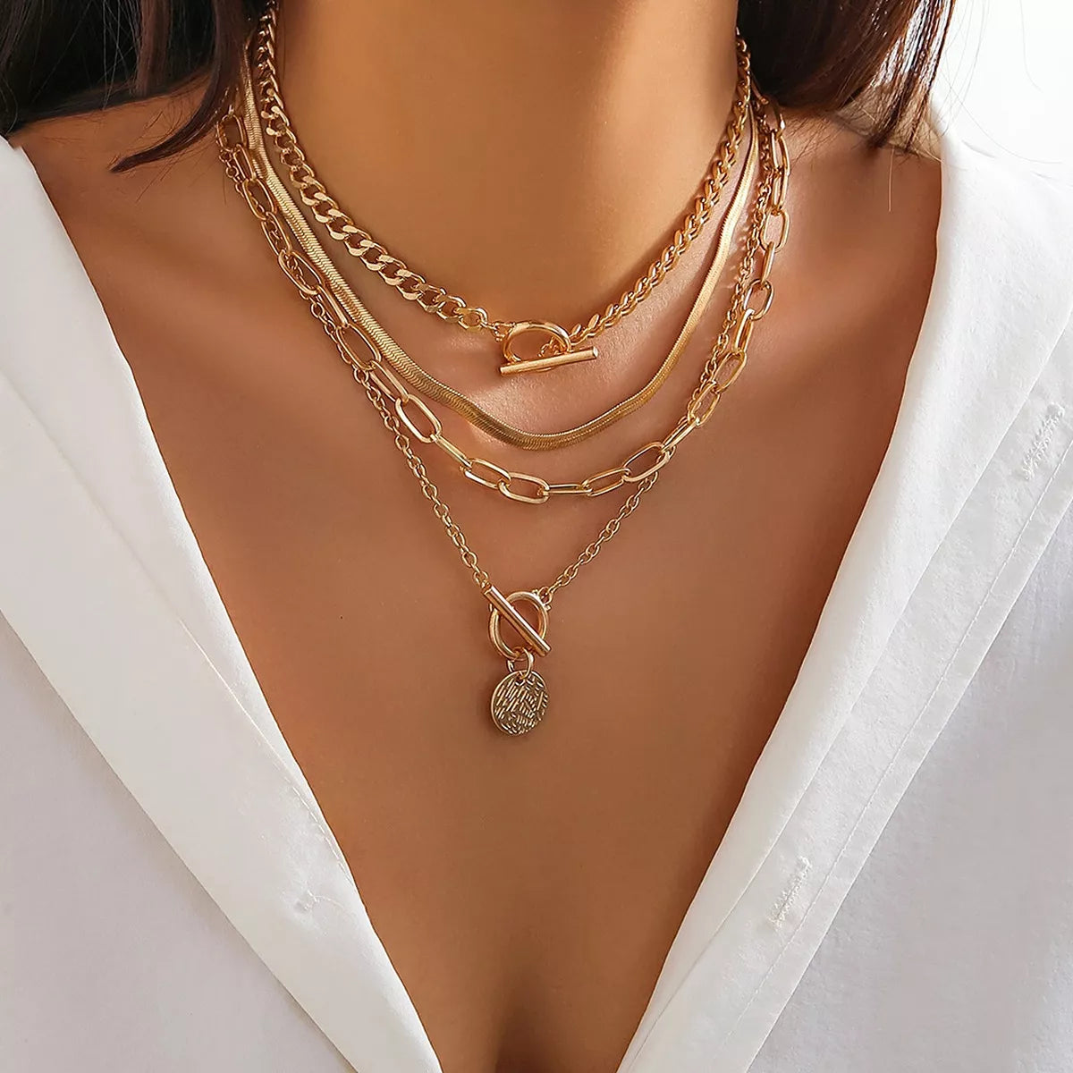 Four layered gold-tone necklaces with coin pendant and mixed chain styles