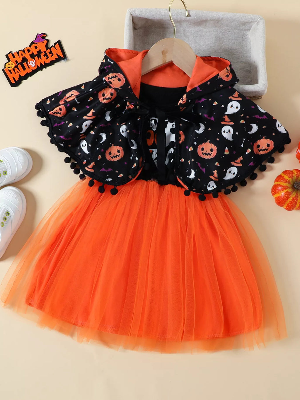 Flat lay of the black Halloween-print cape, black top and orange tulle skirt set.