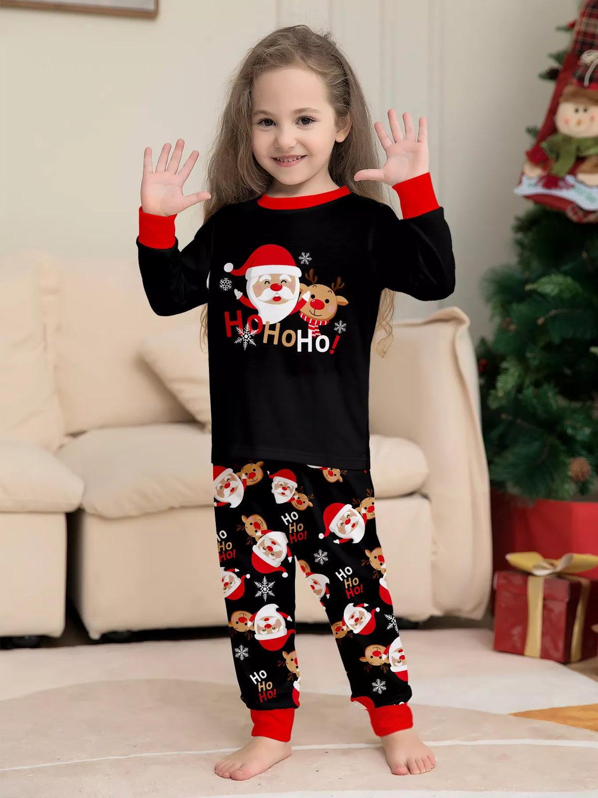 Child wearing the black Santa graphic pajama set with red cuffs.