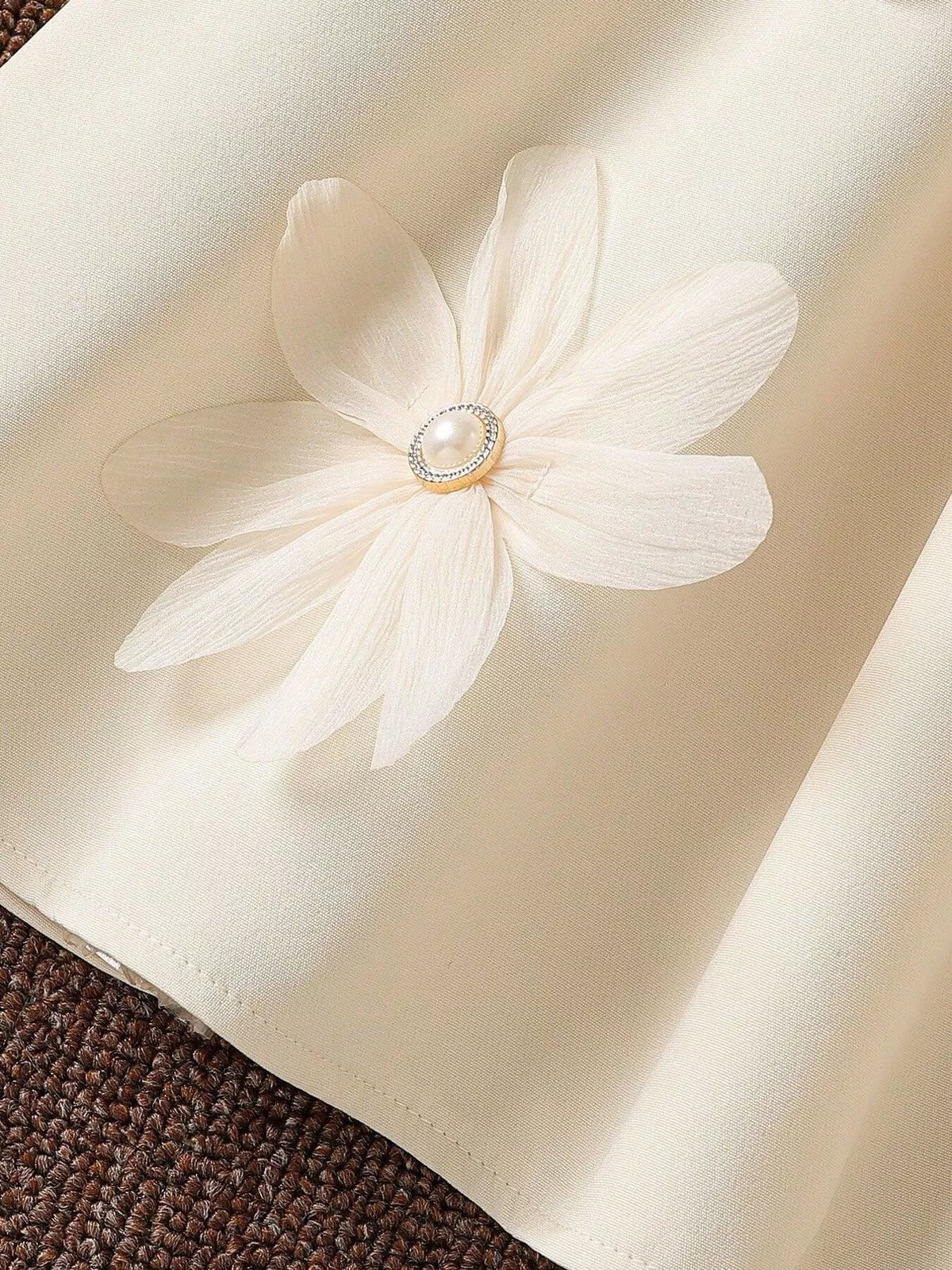 Detail of a flower applique on the cream dress skirt.