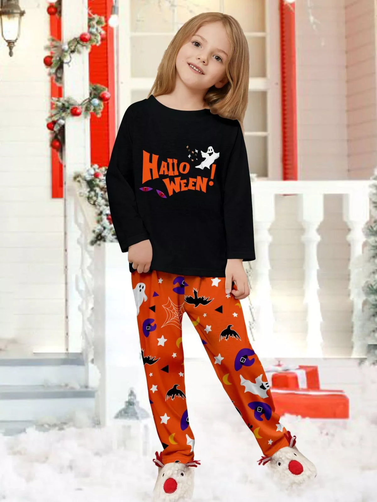 Child wearing a black Halloween graphic top and orange printed pajama pants.