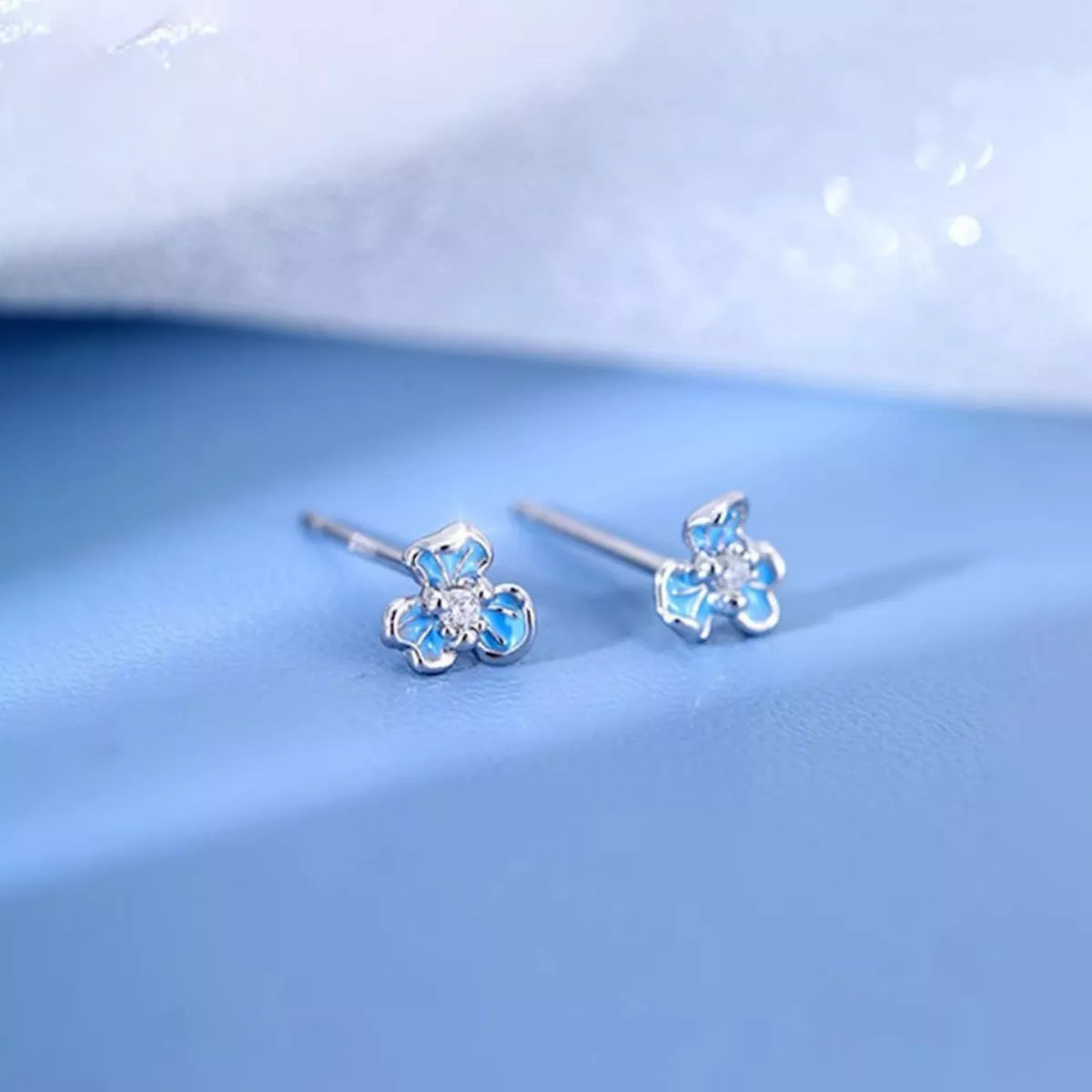 Silver-tone flower stud earrings with blue stones — detail view