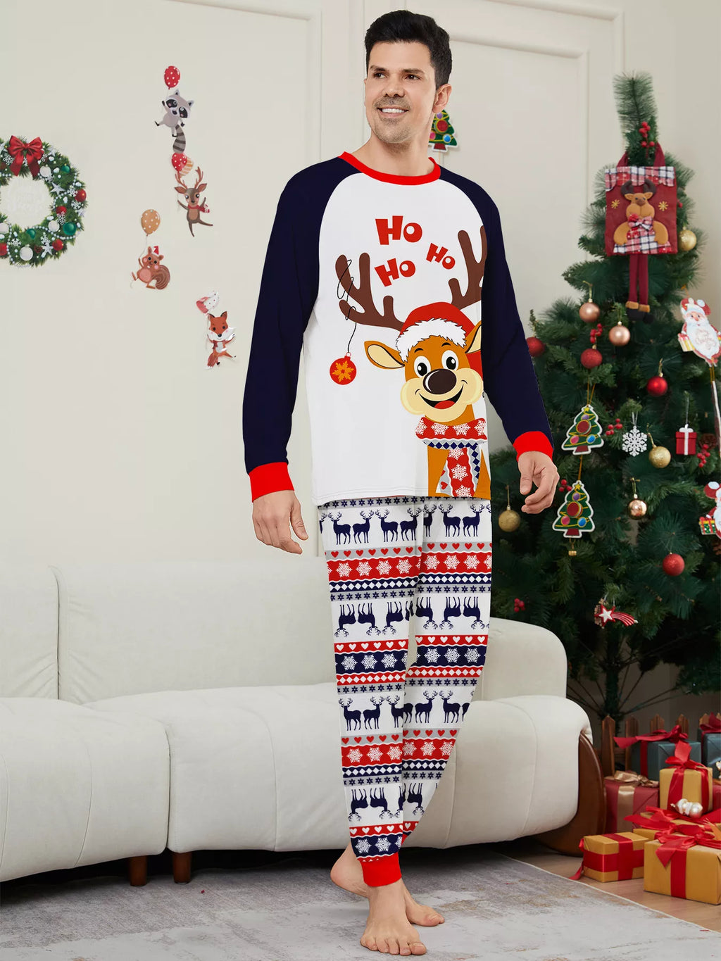 Man modeling a white reindeer Christmas graphic top with navy sleeves and festive striped pajama pants.