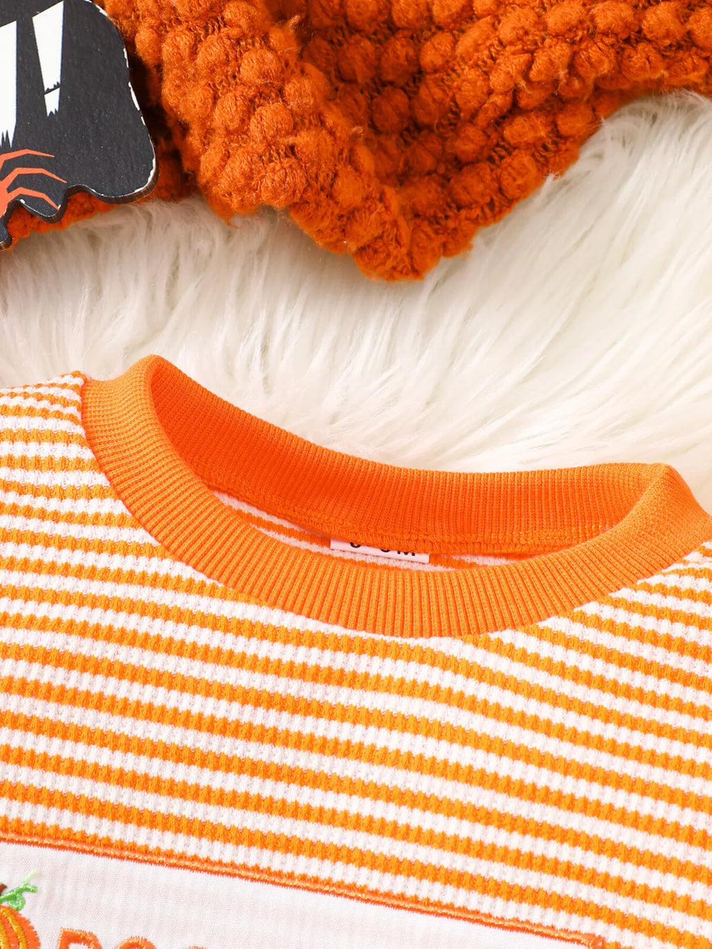 Orange ribbed crew neckline on the striped pajama top