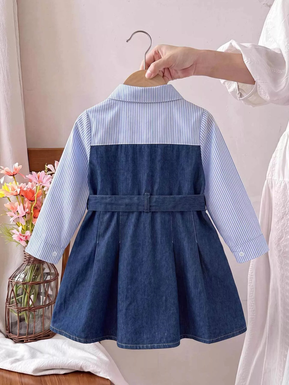 Back view of the blue dress with striped shoulder panel and waist belt.