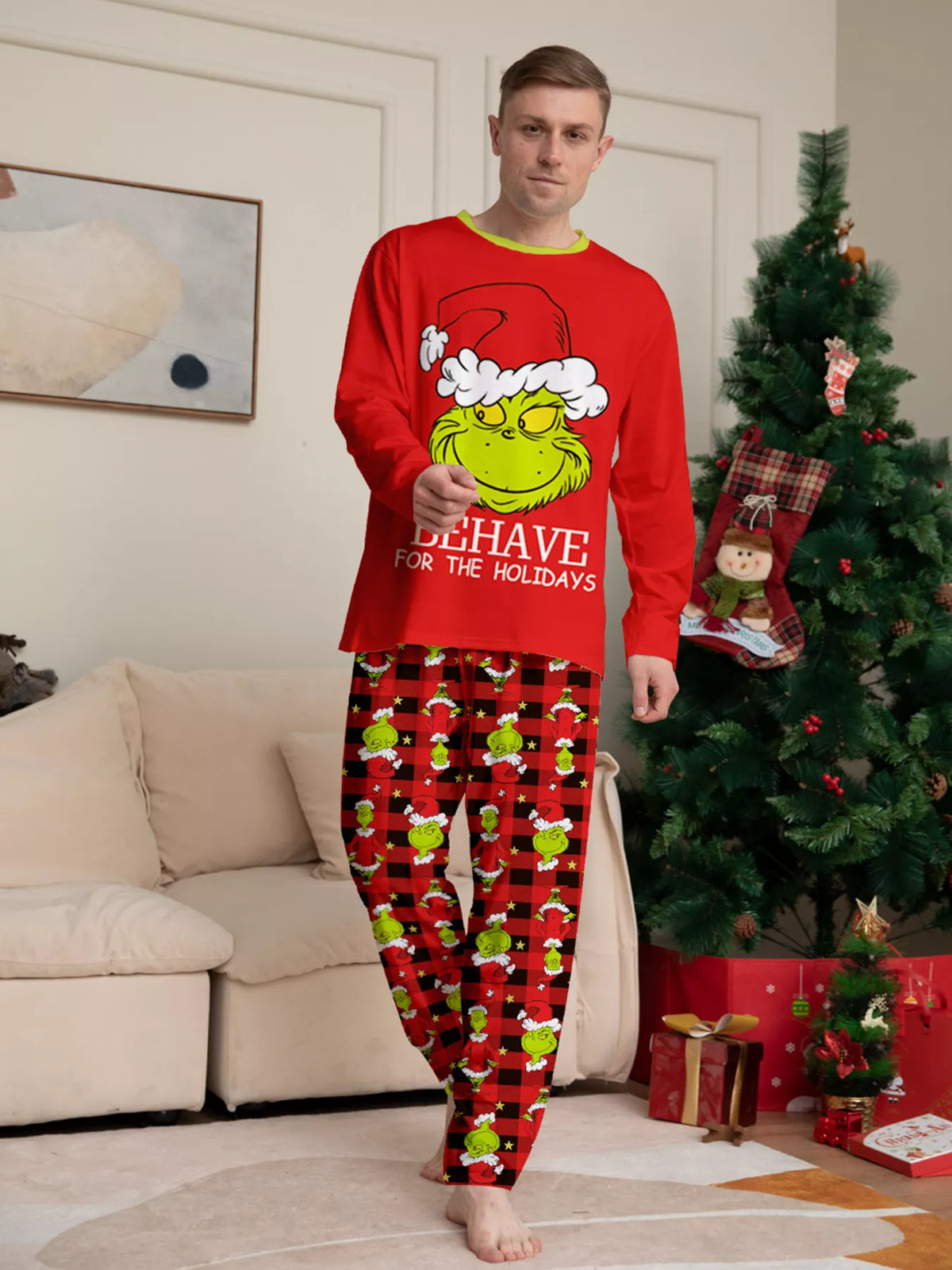 Red matching family Grinch graphic pajama top and Christmas-print pants worn by an adult