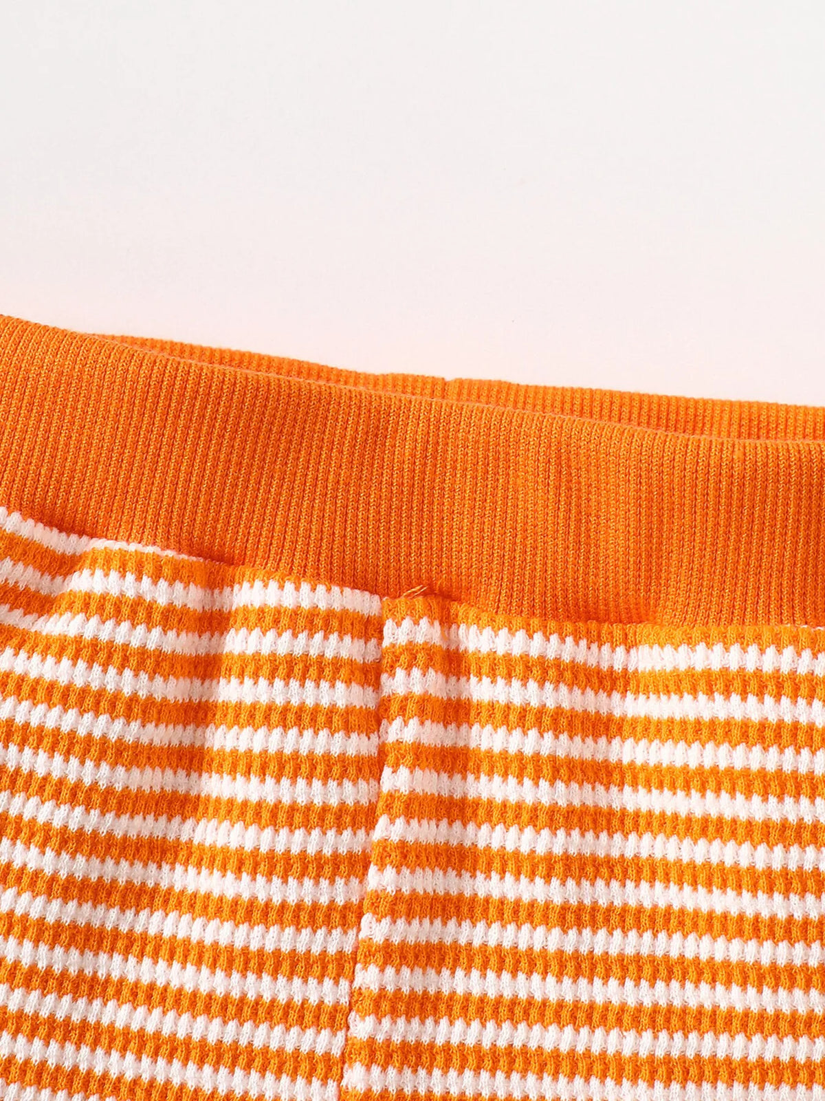 White drawstring waistband on the orange-striped pajama pants