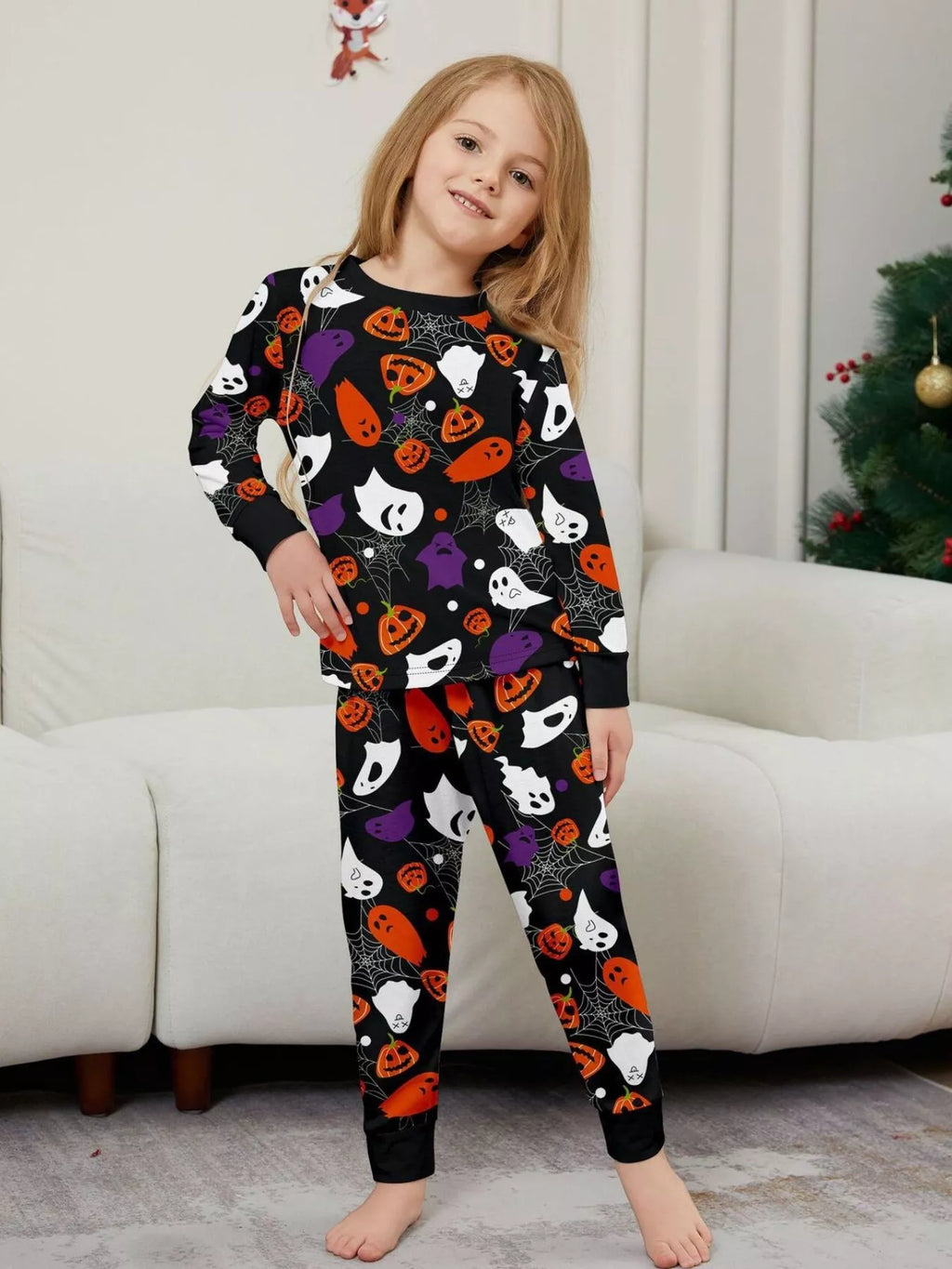 Black matching family pajamas with colorful Halloween ghost and pumpkin print worn by a child