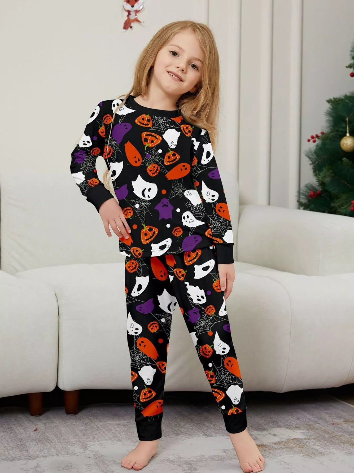 Black matching family pajamas with colorful Halloween ghost and pumpkin print worn by a child