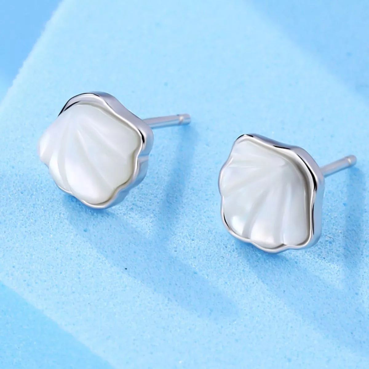 Silver-tone shell-shaped stud earrings with white centers — detail view