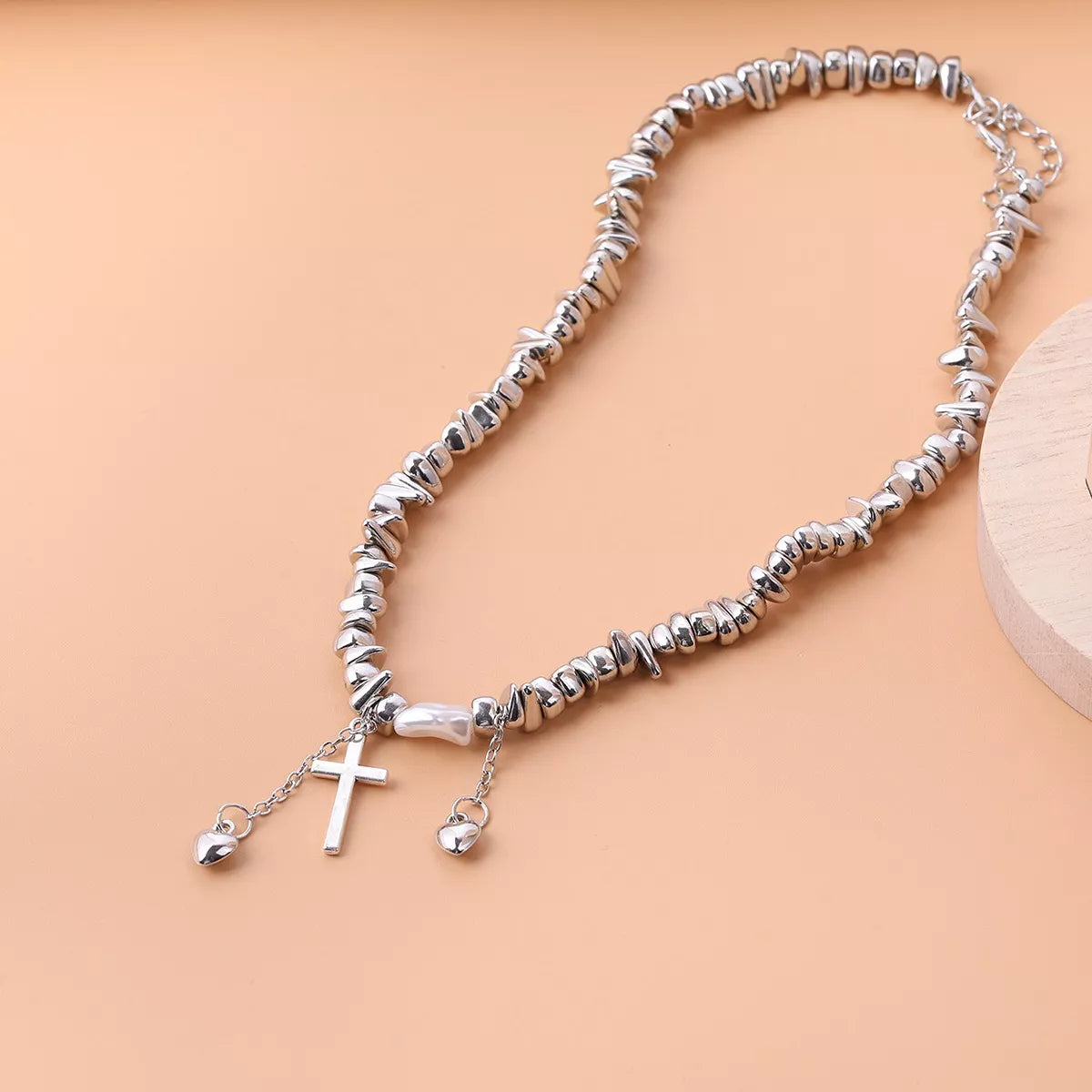 Chunky silver-tone chain necklace with cross and dangling charms — detail view