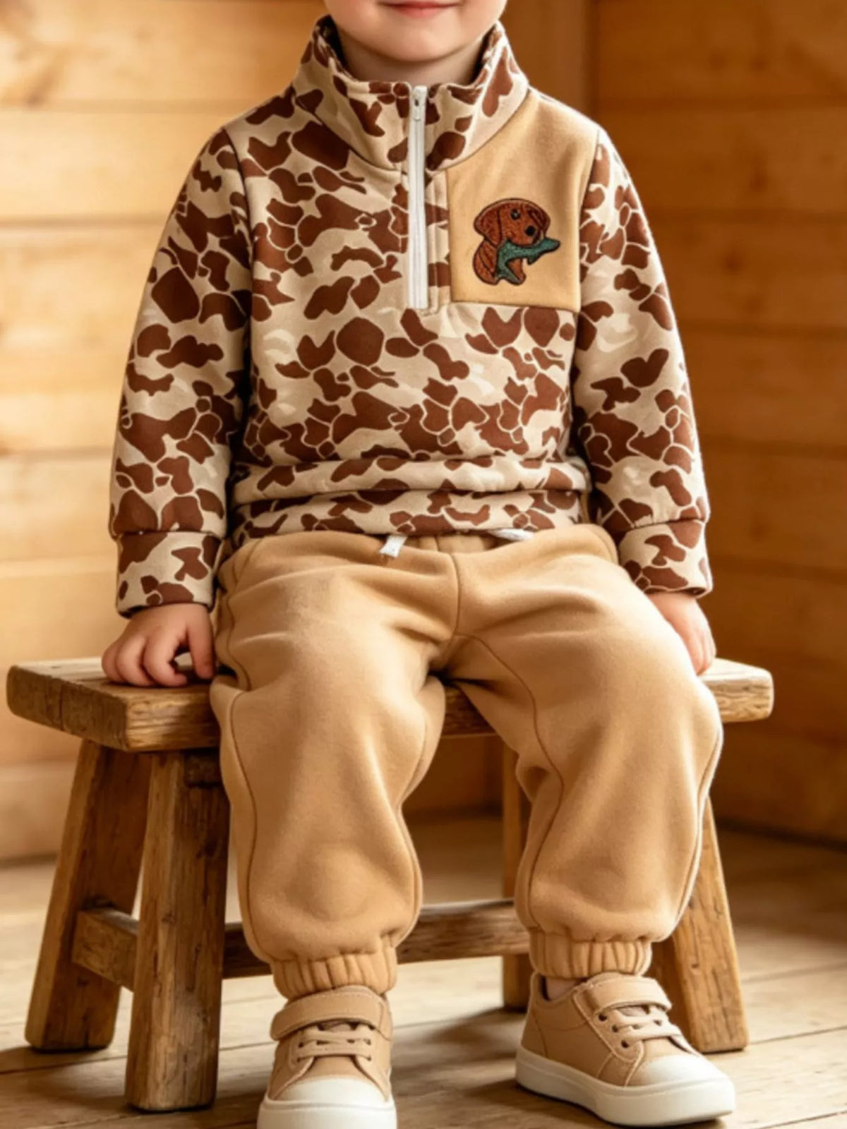 Tan camouflage quarter-zip top and tan joggers worn by a child