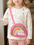 Children’s white multicolor polka-dot long-sleeve top with a pink rainbow bag applique worn by a child