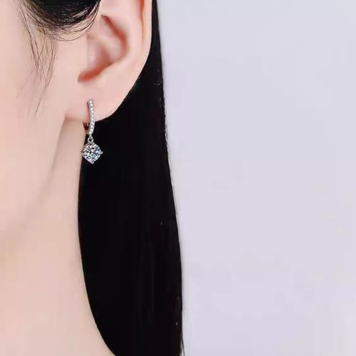 Silver-tone hoop earrings with round halo stone drops worn on a model