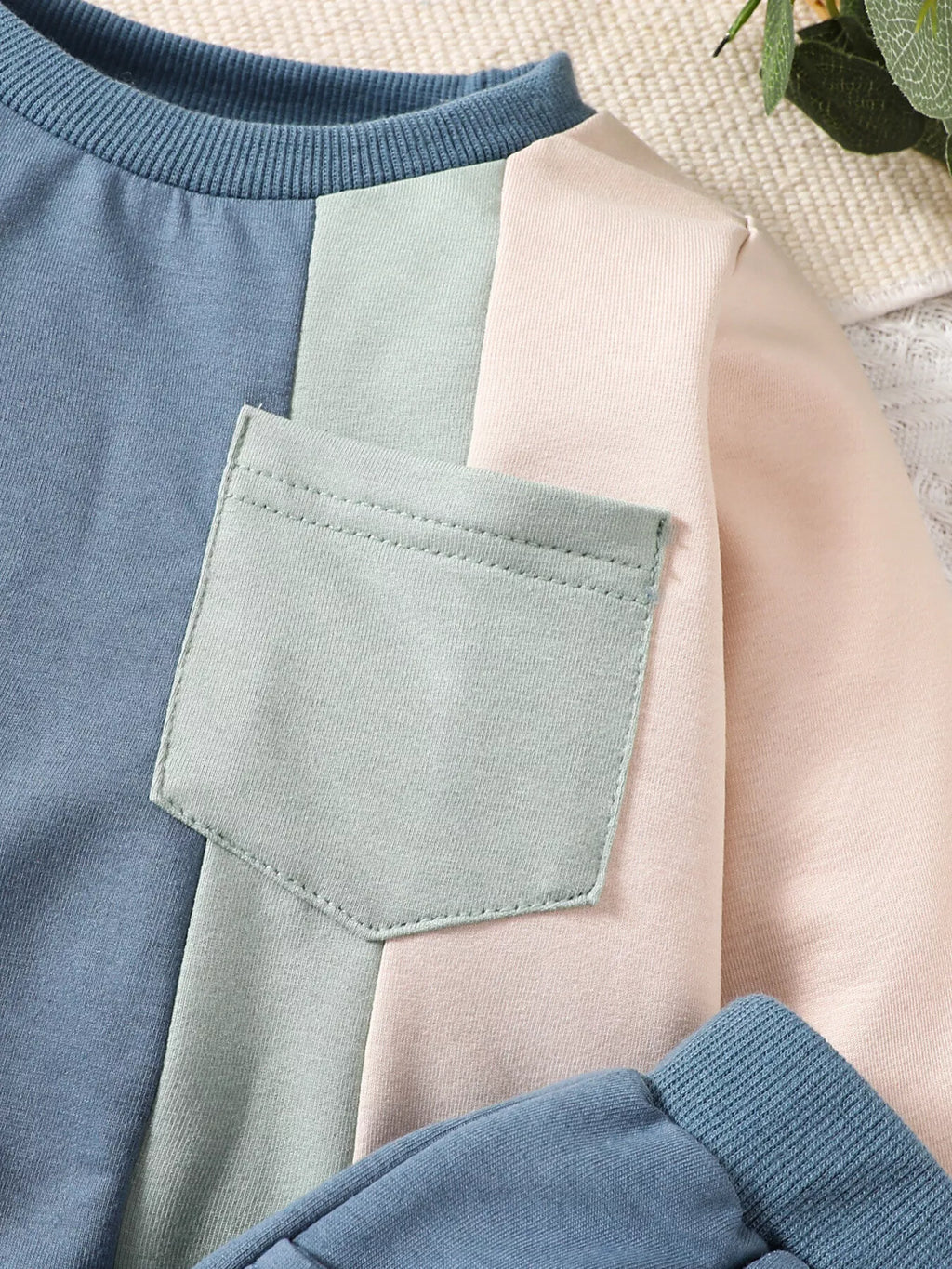 Mint patch pocket and pink sleeve detail on the blue color-block sweatshirt
