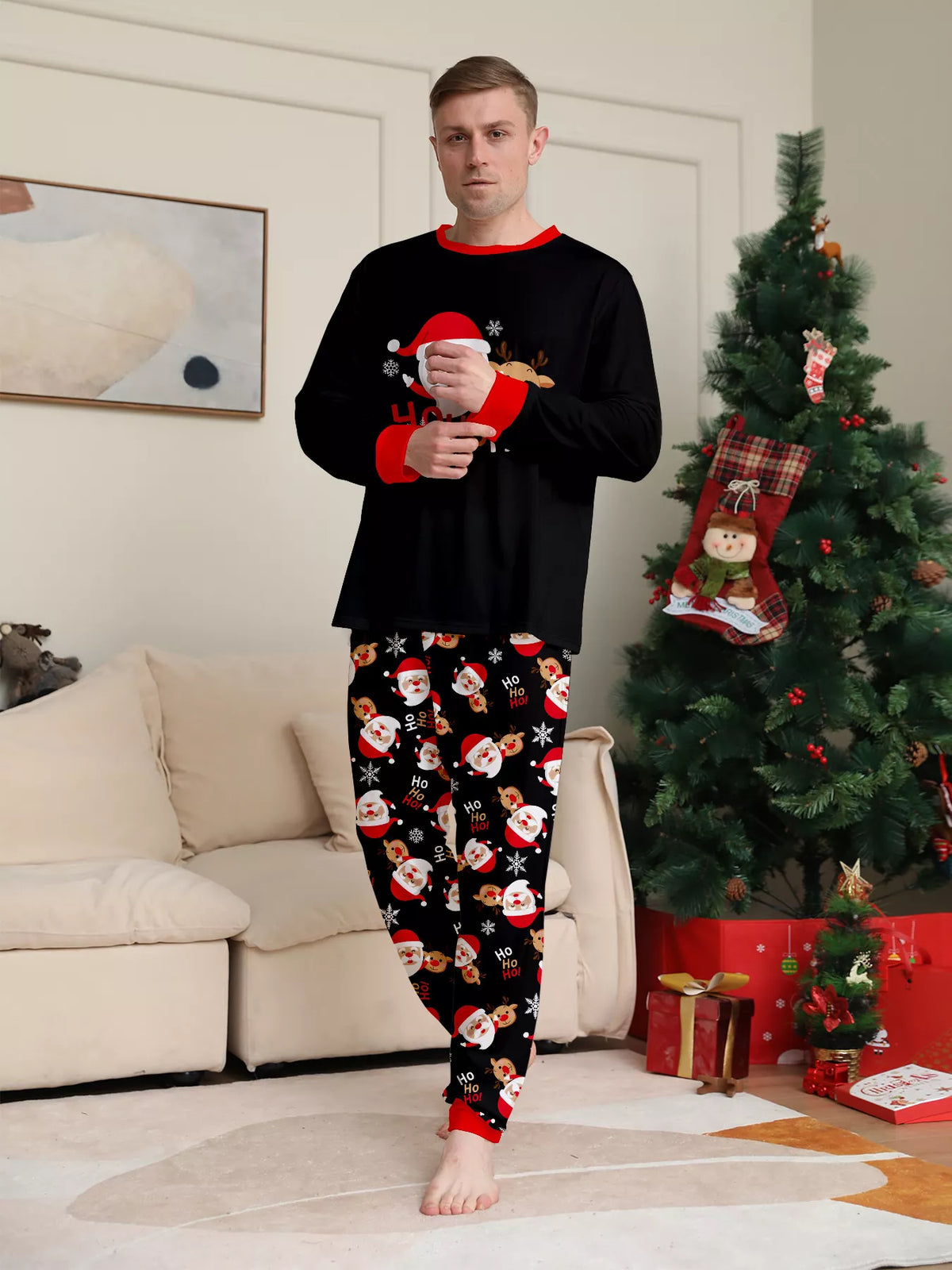 Man modeling the black Santa graphic top and Santa-print pajama pants.