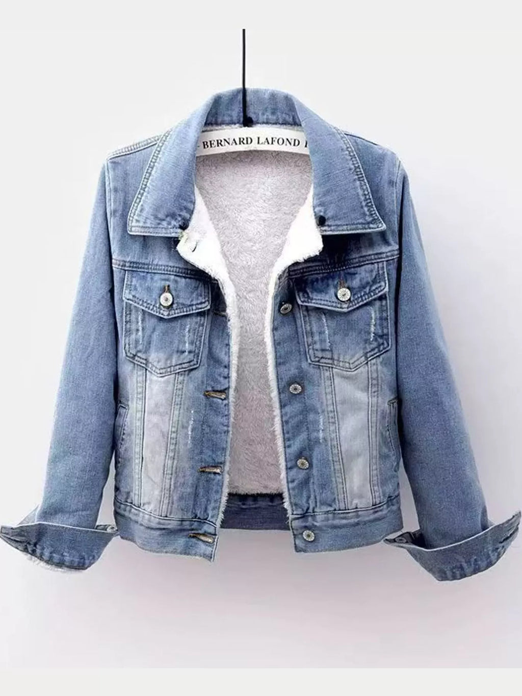 Light-wash denim jacket with white fleece lining, displayed on a hanger.