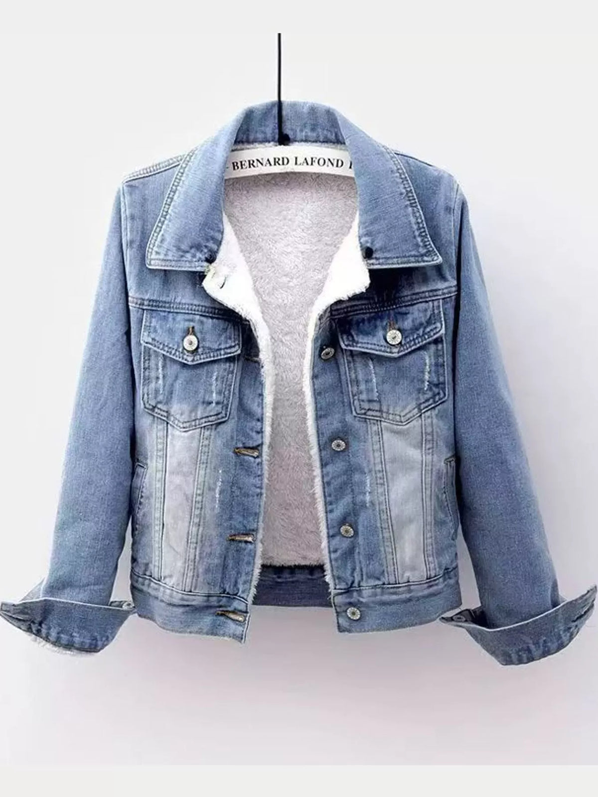 Light-wash denim jacket with white fleece lining, displayed on a hanger.