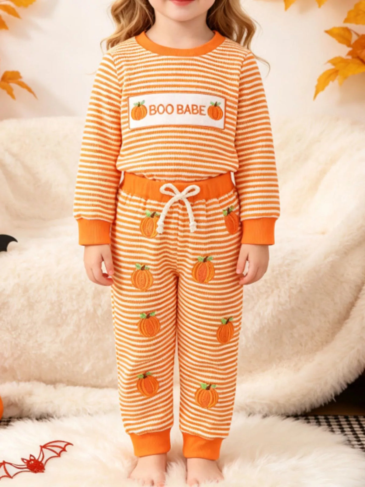 Orange striped BOO BABE pajama top and matching Halloween-print pants worn by a child