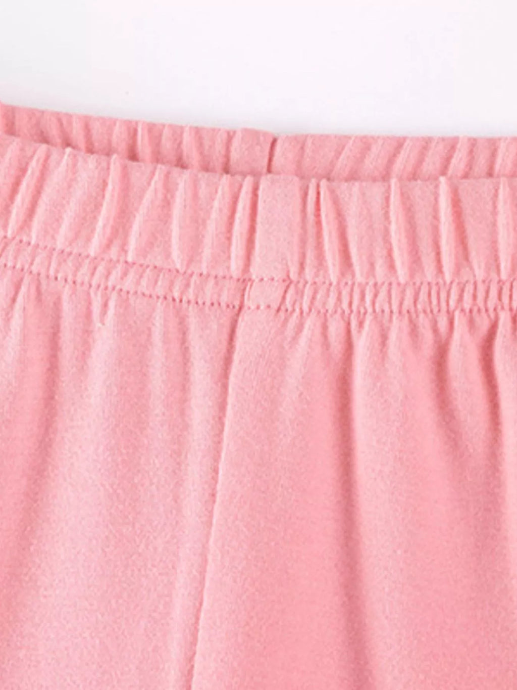 Close-up of the pink top's gathered ruffle hem and leggings waistband.