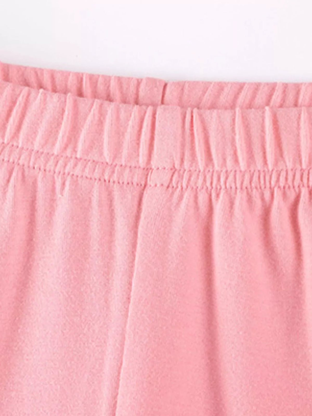 Close-up of the pink top's gathered ruffle hem and leggings waistband.