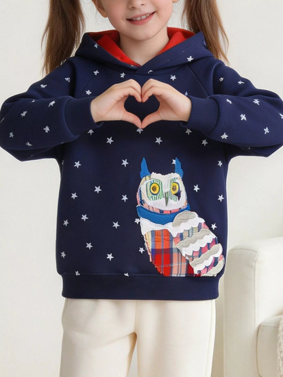 Child modeling the navy star-print hoodie with owl applique and red hood lining.
