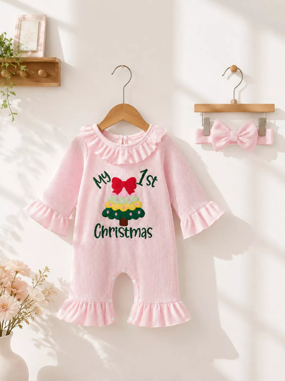 Pink My 1st Christmas romper with ruffle collar and flared legs displayed on a hanger.