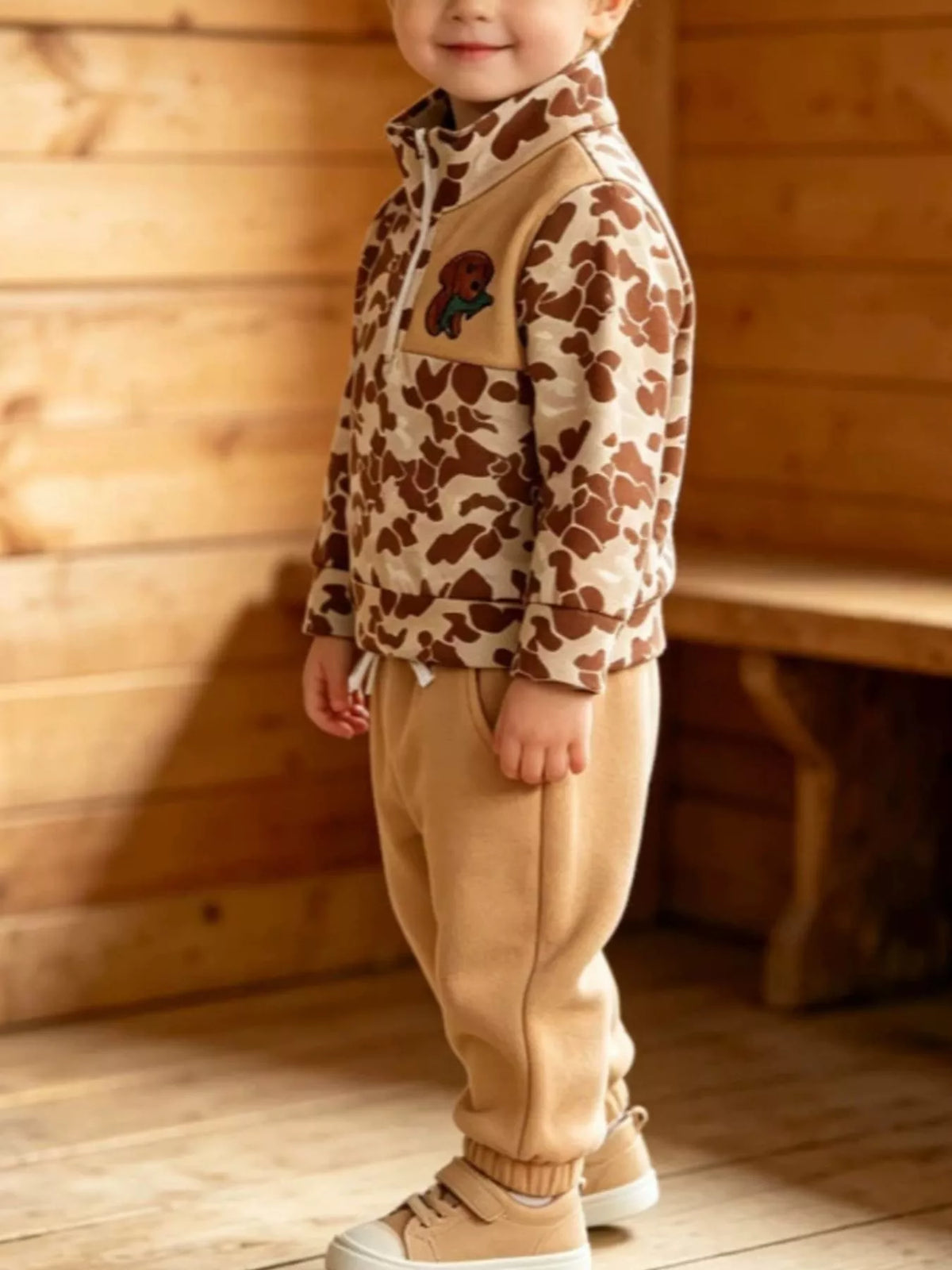 Tan camouflage quarter-zip top and tan joggers worn by a child