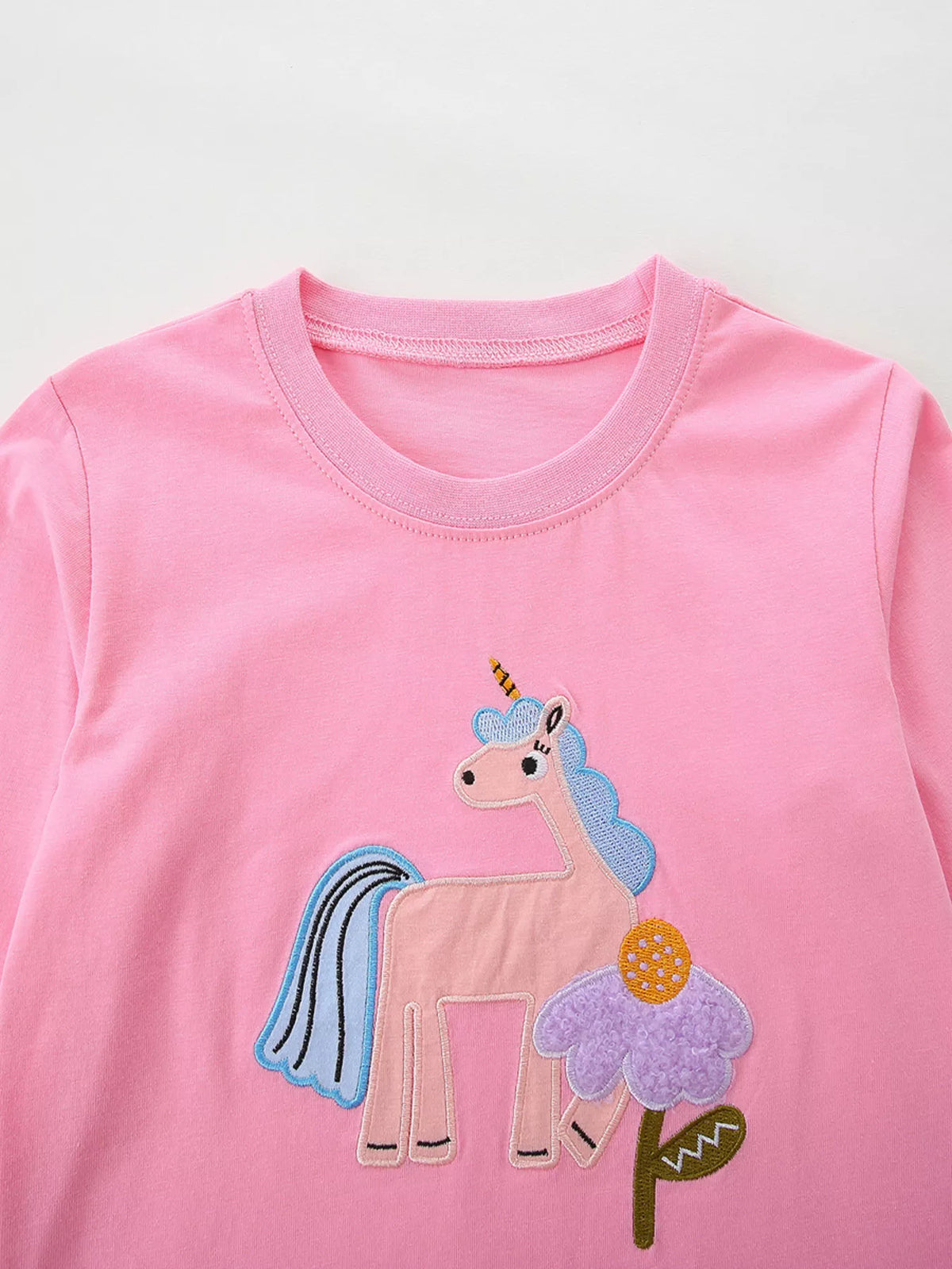 Pink children’s long-sleeve top with a colorful unicorn graphic