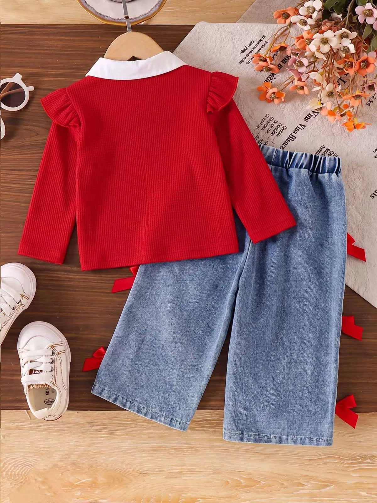 Children’s red bow-embellished sweater with white collar and blue jeans with red bows — back view