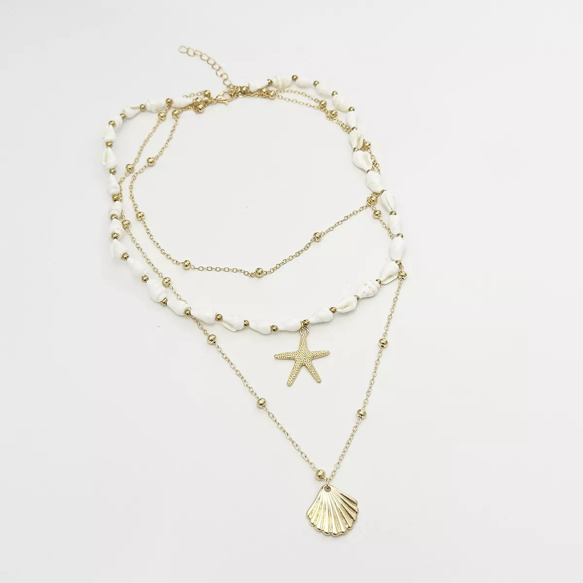 Layered gold-tone shell and starfish charm necklace — detail view