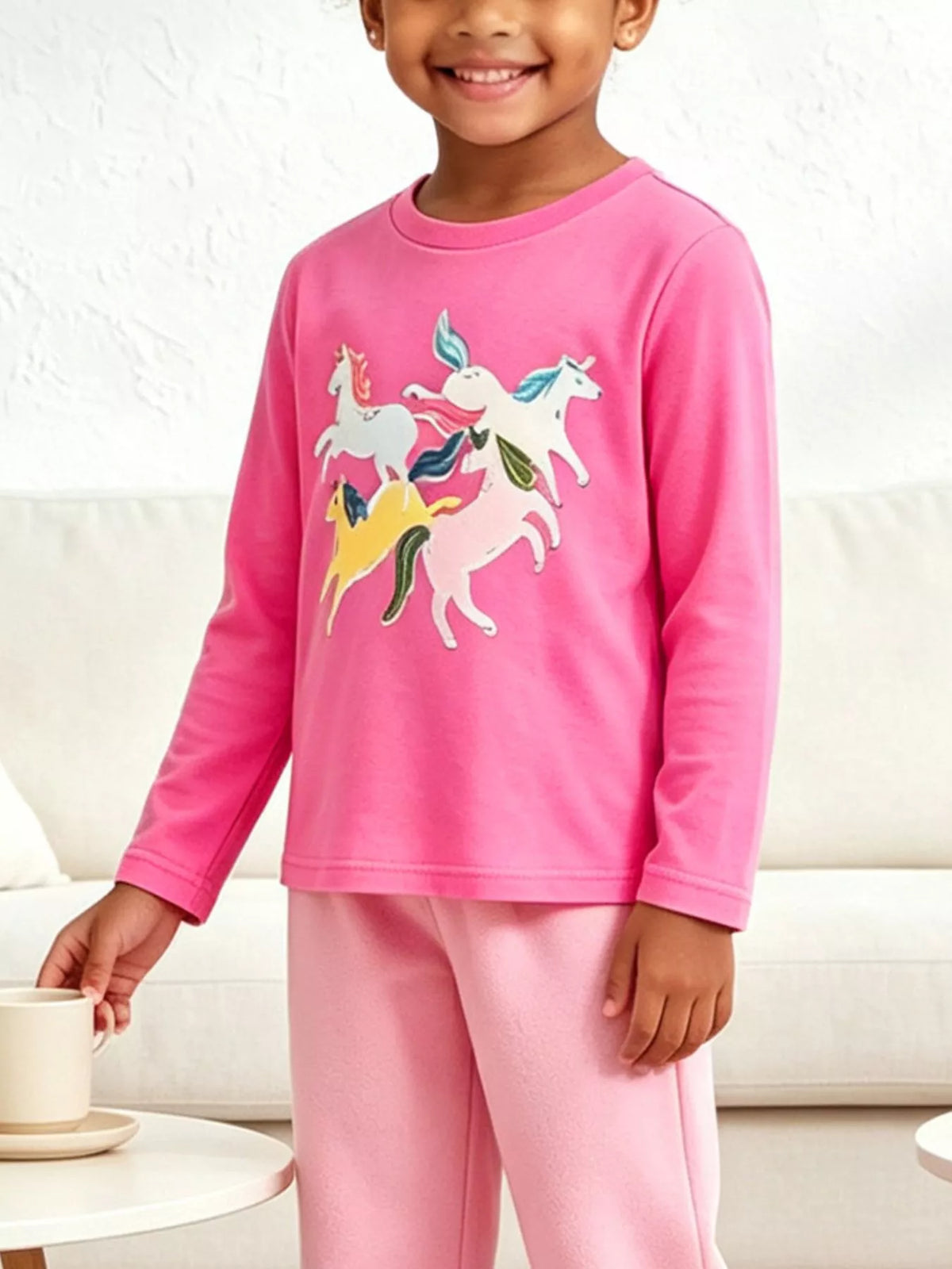 Children’s pink long-sleeve T-shirt with colorful unicorn graphics worn by a child
