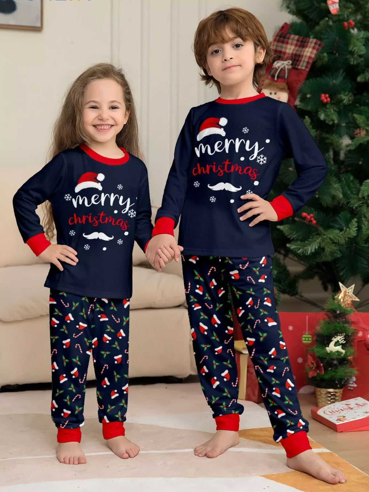 Two children wearing matching navy Merry Christmas tops and printed pajama pants.