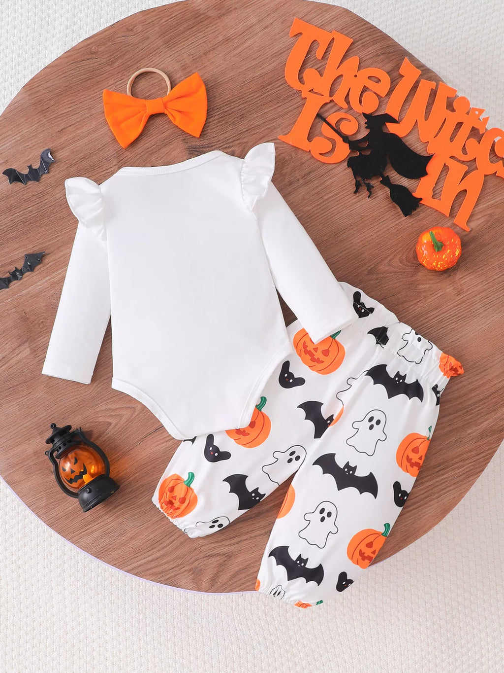 Back flat lay of the white bodysuit, pumpkin-and-ghost pants and orange bow headband.