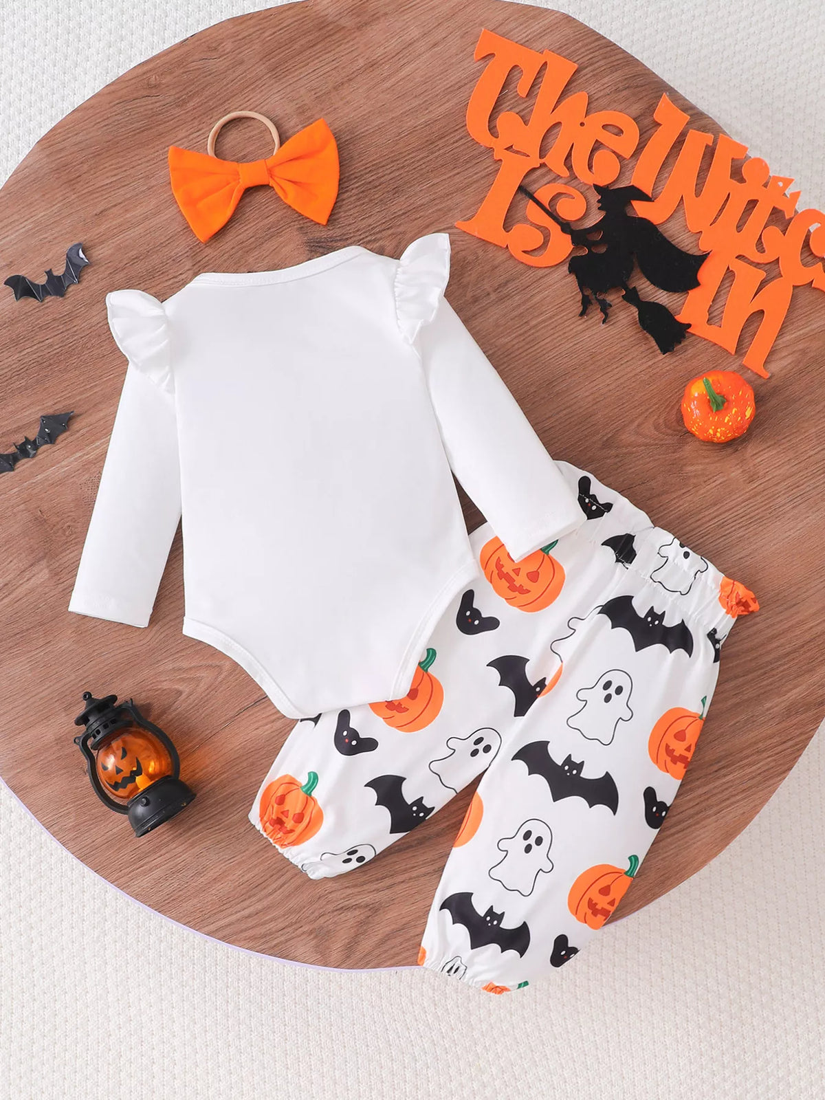 Back flat lay of the white bodysuit, pumpkin-and-ghost pants and orange bow headband.
