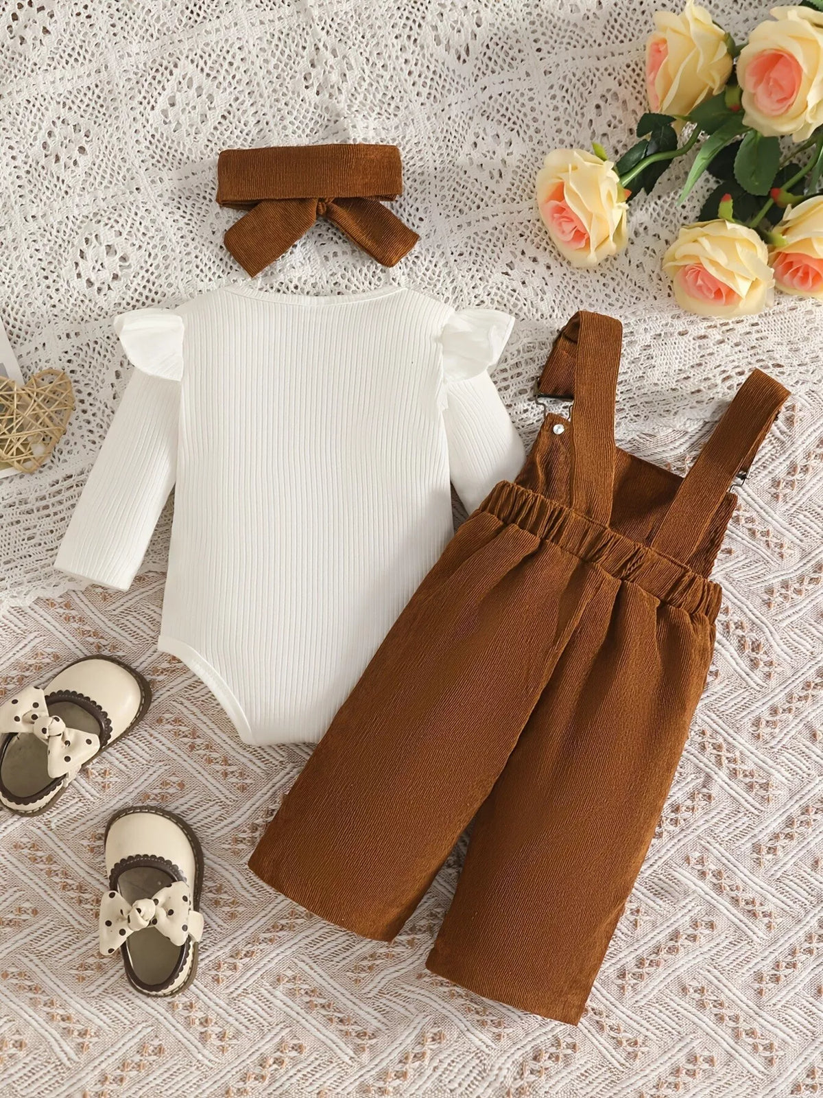 White ribbed baby bodysuit with brown bow-embroidered overalls and matching headband displayed flat