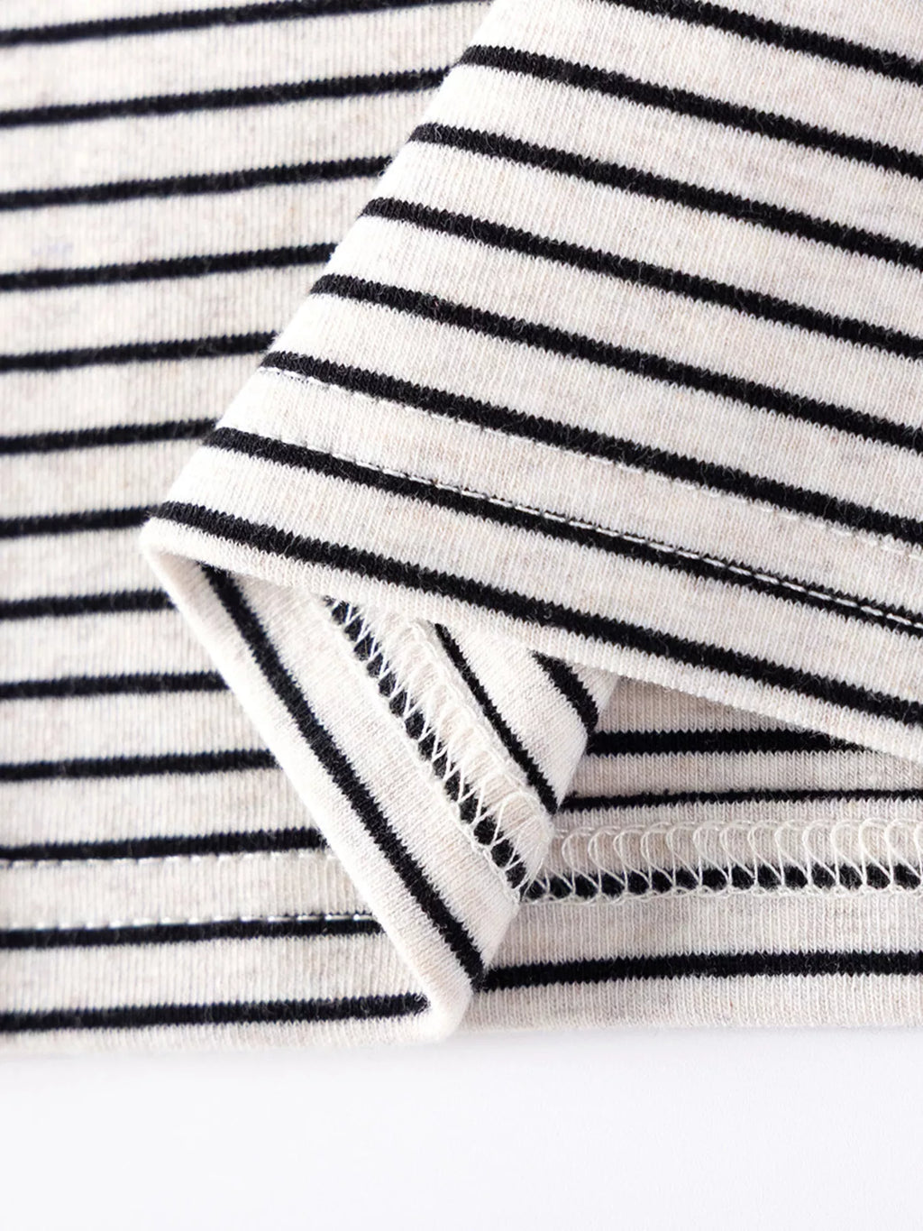 Close-up of the striped top's sleeve cuff and hem stitching.