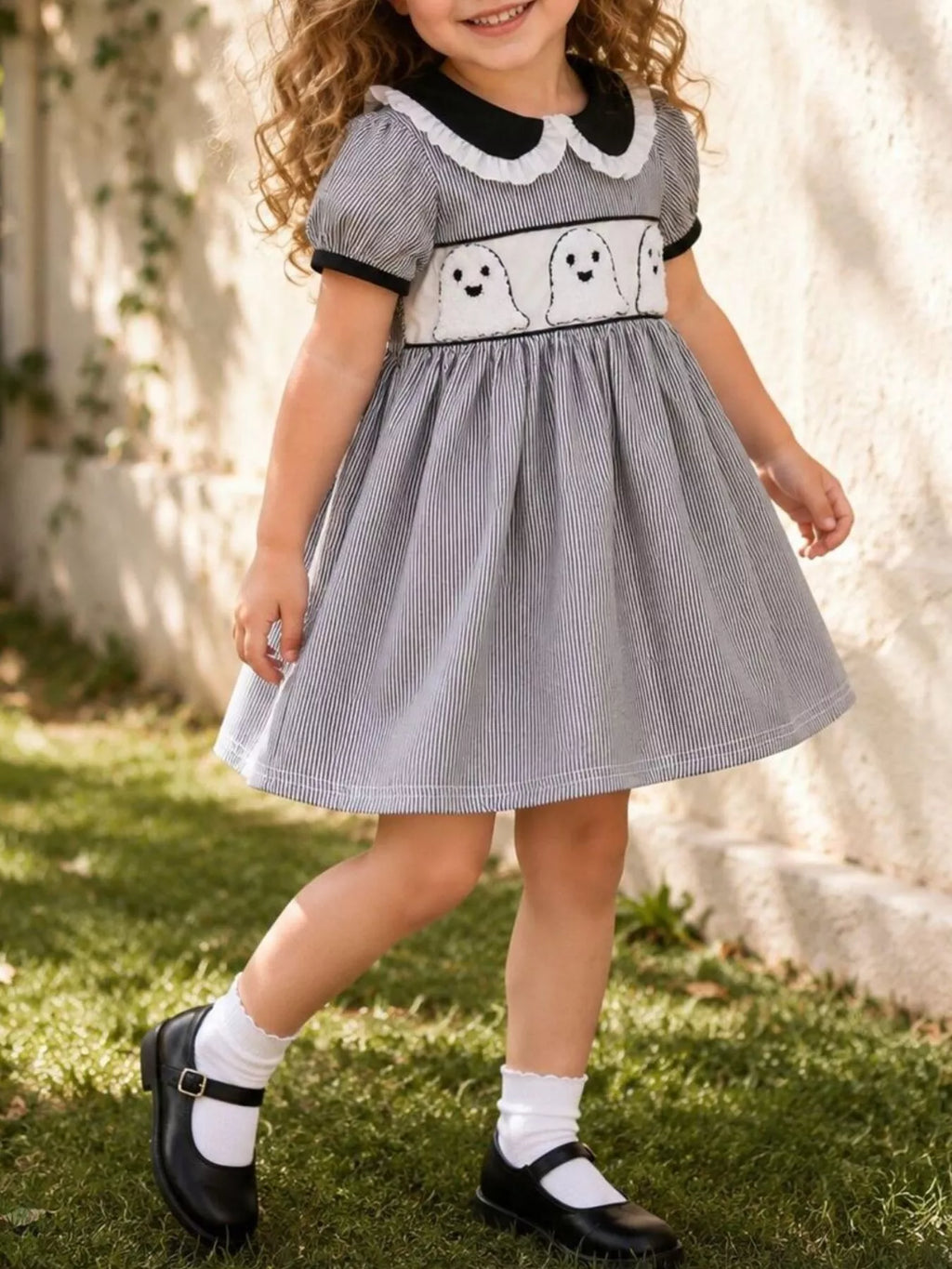 Child wearing a gray short-sleeve dress with white collar and ghost-print waistband.