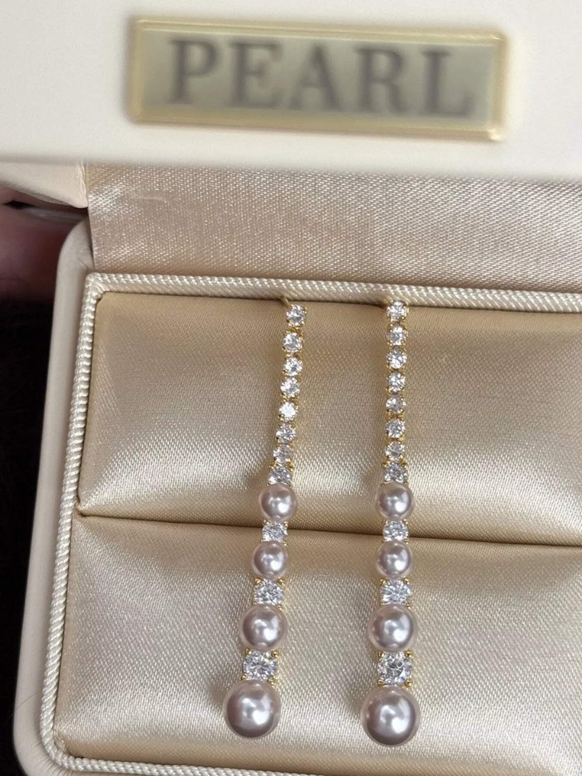 Gold-tone long pearl-like bead and clear stone drop earrings — detail view
