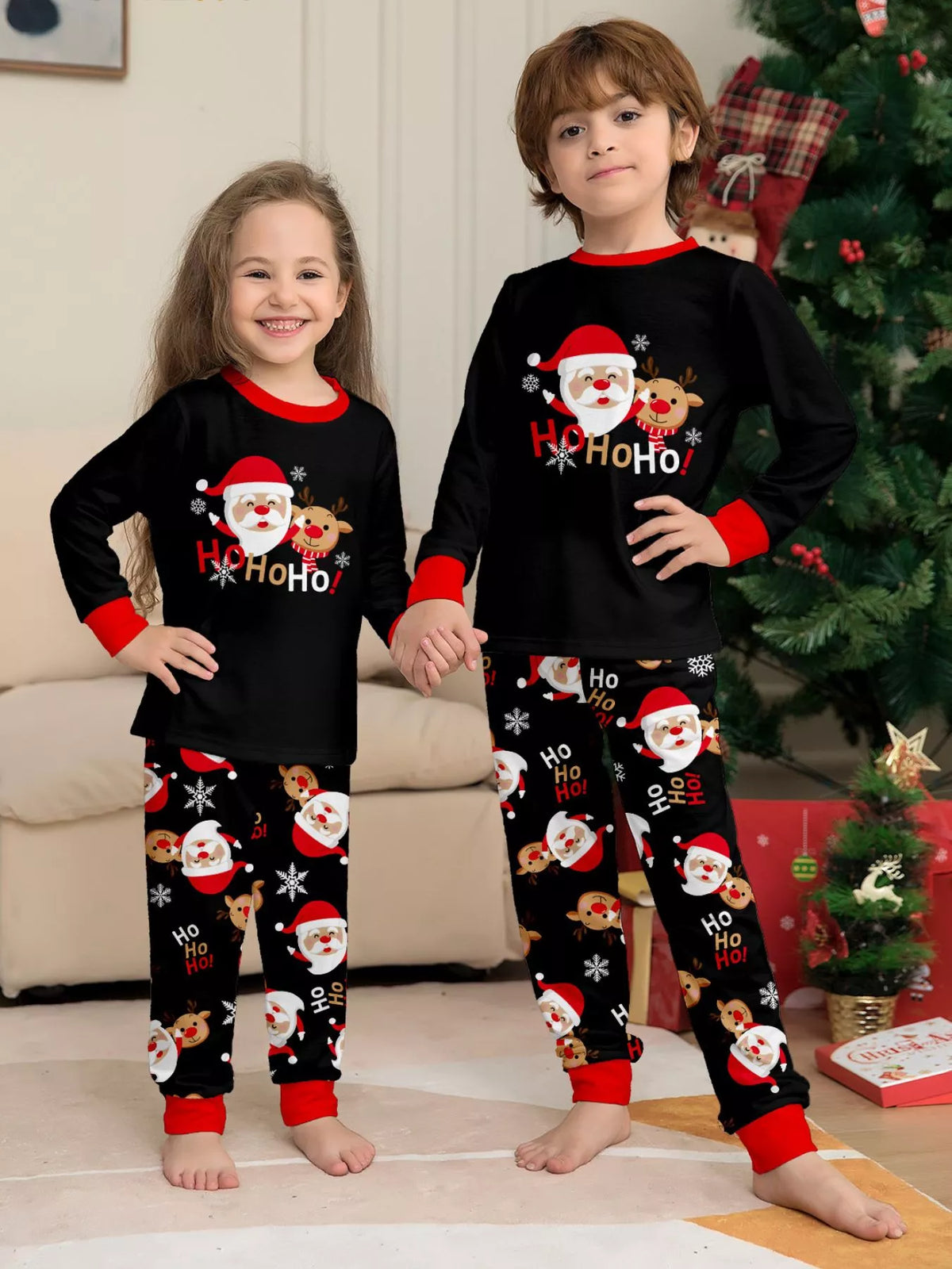 Two children wearing matching black Santa graphic pajamas.