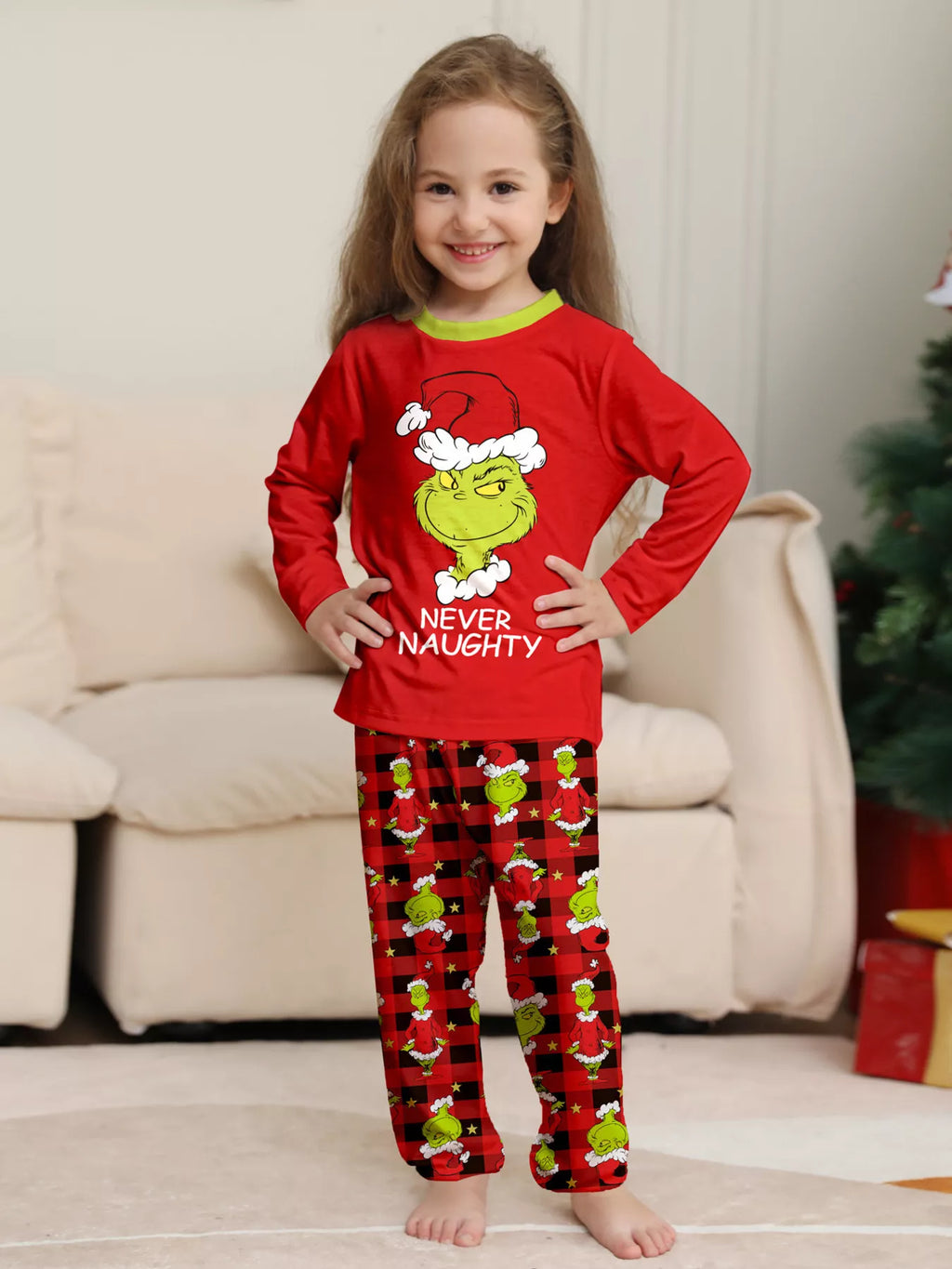 Red matching family Grinch graphic pajama top and Christmas-print pants worn by a child