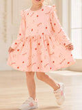 Child wearing a pink long-sleeve strawberry-and-bunny print dress with shoulder ruffles.