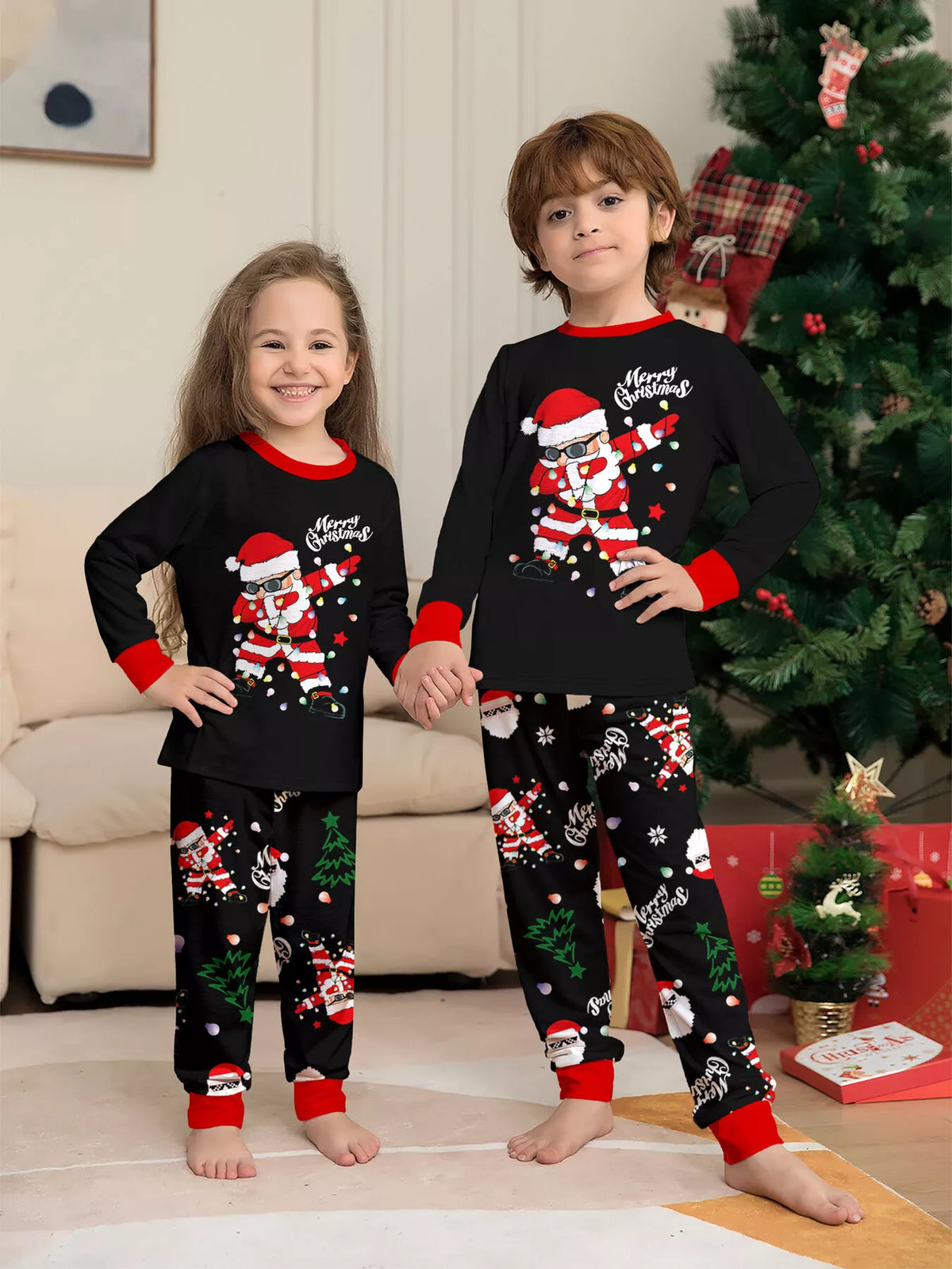Two children wearing matching black Santa graphic tops and Christmas-print pajama pants.