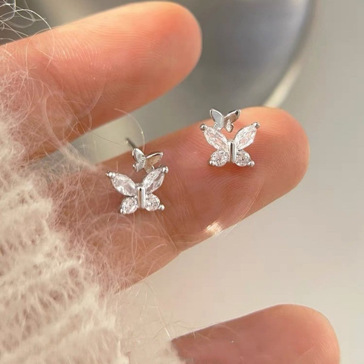 Silver-tone butterfly stud earrings with clear stones — detail view