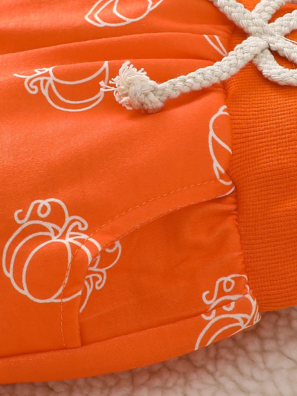 White drawstring waistband on the orange pumpkin-print pants