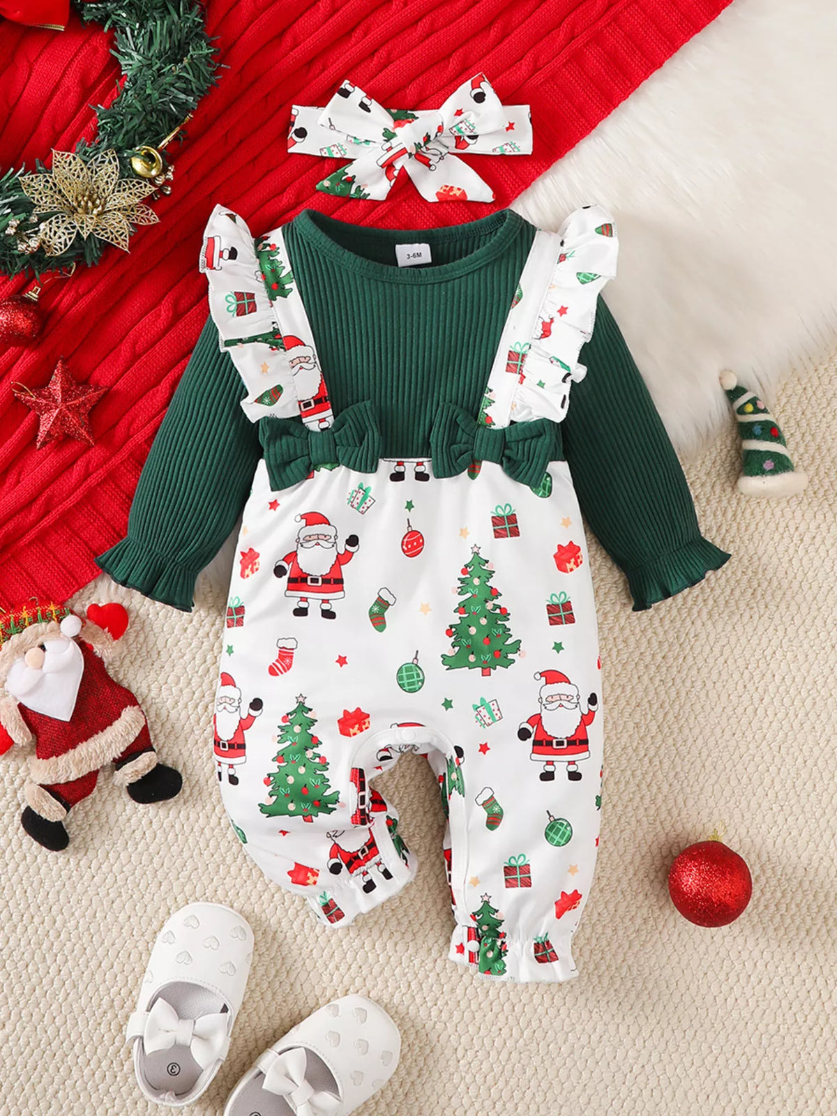 Children’s green and white Santa-print ruffle-trim jumpsuit with matching headband displayed flat