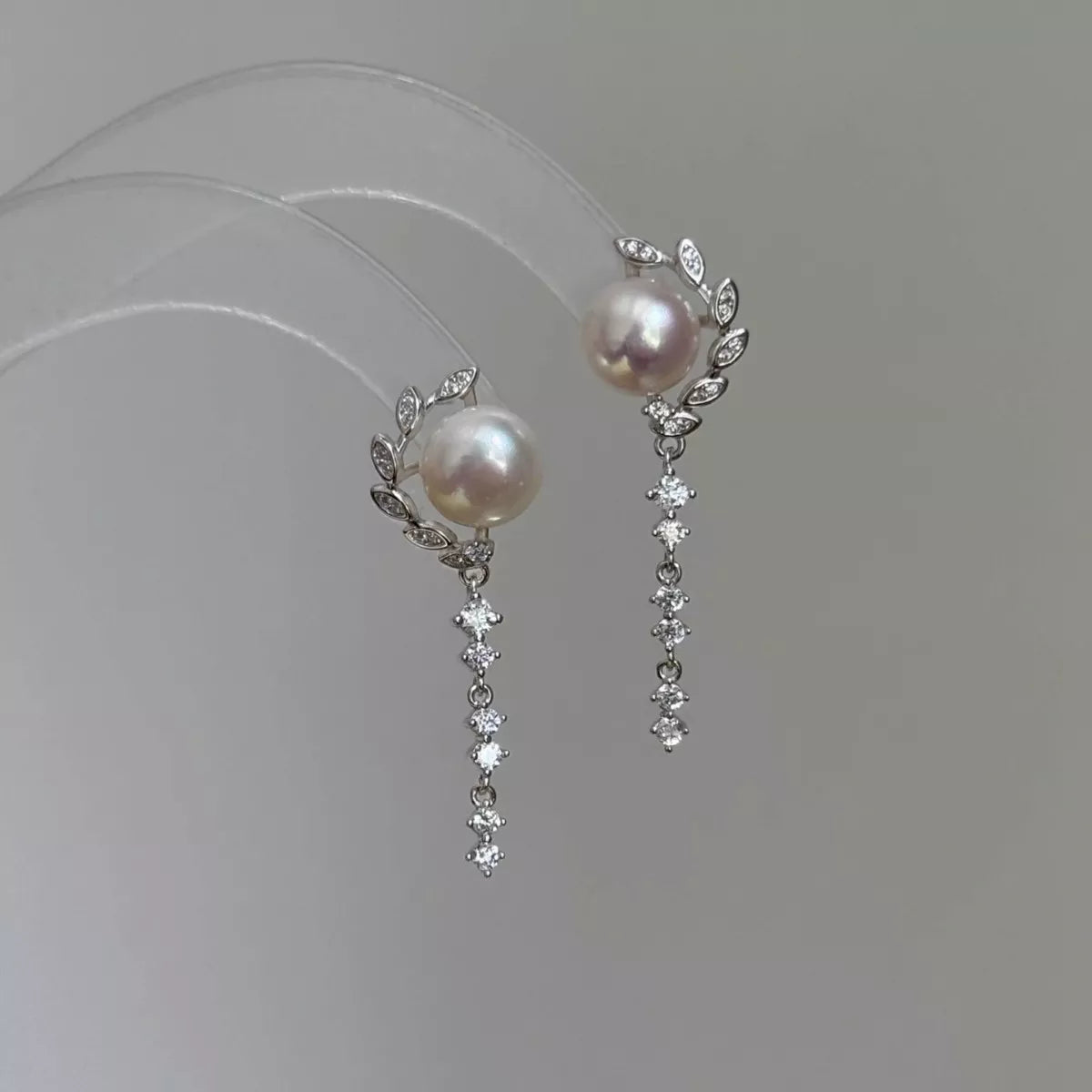 Pearl-like bead drop earrings with long dangling clear stone chains — detail view